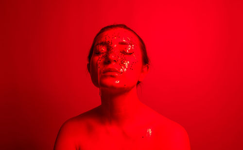 Close-up of woman with water and star shape decoration against red background