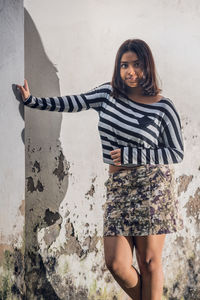 Portrait of woman standing against wall