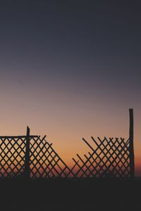 Silhouette fence against sky during sunset
