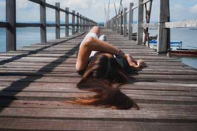 Rear view of woman relaxing on pier