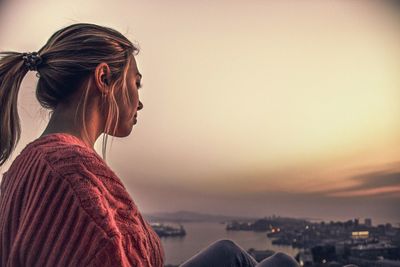 Side view of woman looking at cityscape against sky