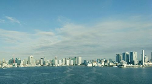 Sea by cityscape against sky