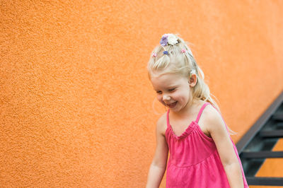 Portrait of young woman standing against yellow wall