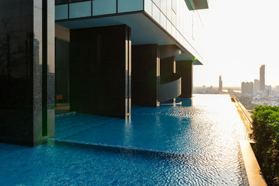 Buildings by swimming pool in city against clear sky