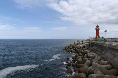 Lighthouse by sea against sky