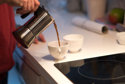 Close-up of hand pouring coffee in cup