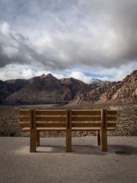 Empty bench on mountain range against sky