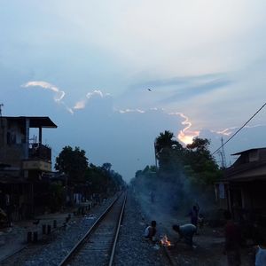 People on railroad tracks against sky