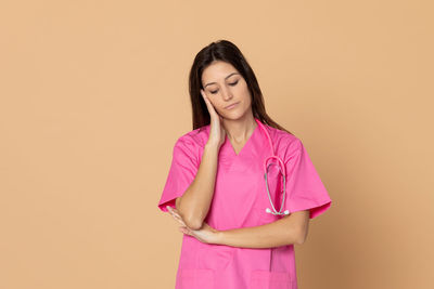 Young woman standing against pink background