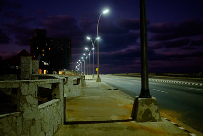 Illuminated street against sky at night