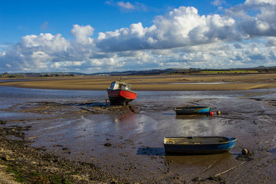 Boat moored on beach against sky