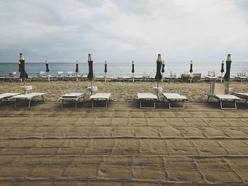 Chairs on beach against sky