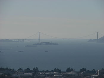 View of suspension bridge over sea during foggy weather