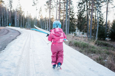 Young girl carrying cross country skis on a slope in sweden
