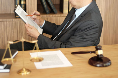 Midsection of man holding paper at table