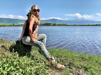 Portrait of woman sitting on rock by lake