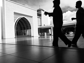 Silhouette people standing on tiled floor by building