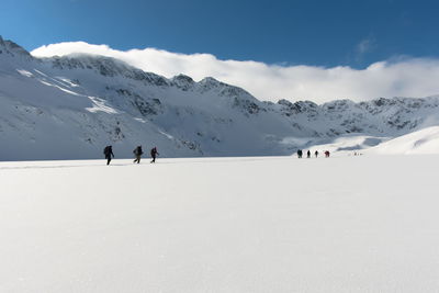 People walking on snowcapped mountain against sky