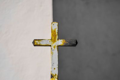 Close-up of rusty cross against wall