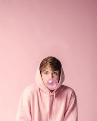 Portrait of man covering face against pink background