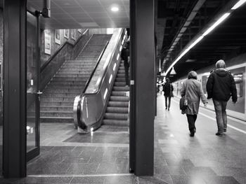 Full length rear view of people walking in underground subway station near steps