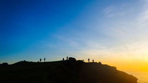 Silhouette people on landscape against clear sky