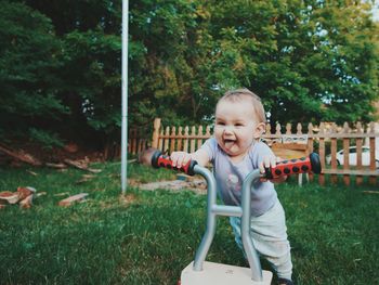 Cheerful little baby with walker on lawn