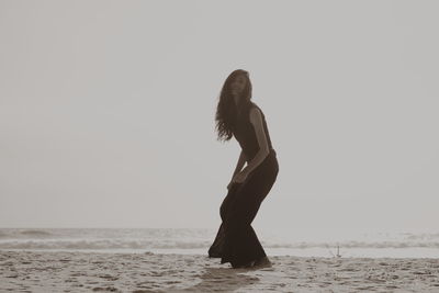 Woman standing in sea against clear sky