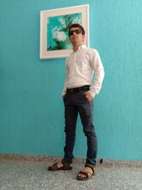 Full length of young man standing against wall