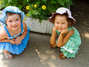 Playful girls crouching by plants