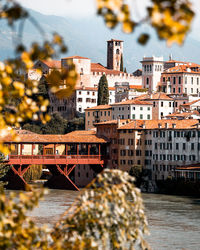 River side village with tree and bridge and castle on top of the hill.