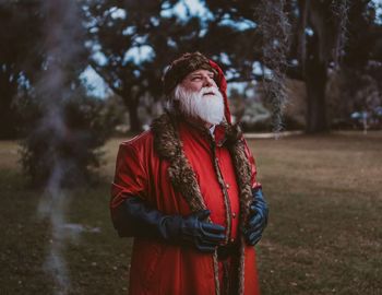 Man looking away while standing on tree in forest