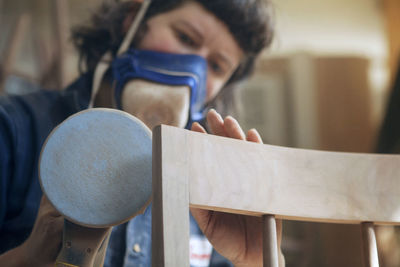 Female carpenter sanding wooden chair