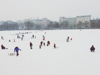 People on snow covered landscape against clear sky