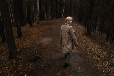 Rear view of woman looking away while walking in forest