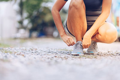 Low section of athlete tying shoelace on street