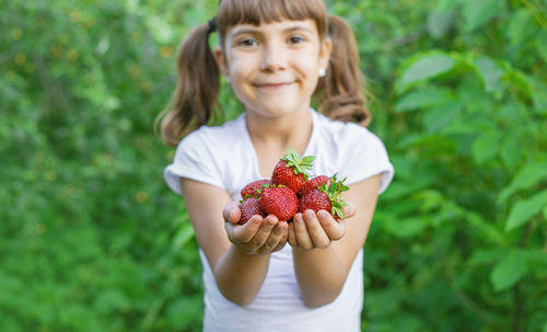 Portrait of cute girl holding strawberries