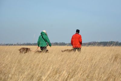 People with dogs walking on agricultural field