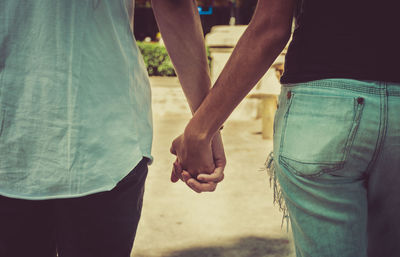 Midsection of friends holding hands outdoors