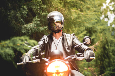 Full length of young man riding bicycling on plants