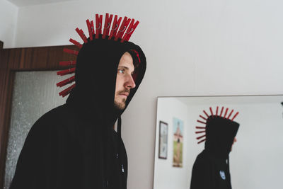 Rear view of punk man against mirror and white wall