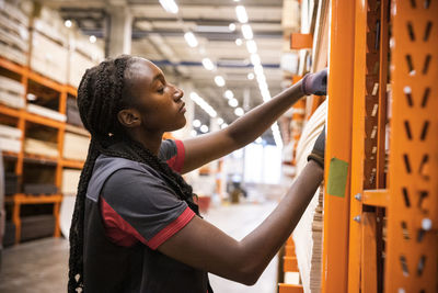 Female sales staff examining plywood at hardware store