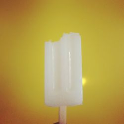 Close-up of ice cream cone against yellow background