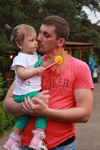 Father carrying cute daughter while standing on road against trees