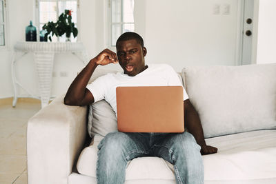 Young man looking away while sitting on sofa