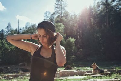 Young woman with horse standing by trees against sky