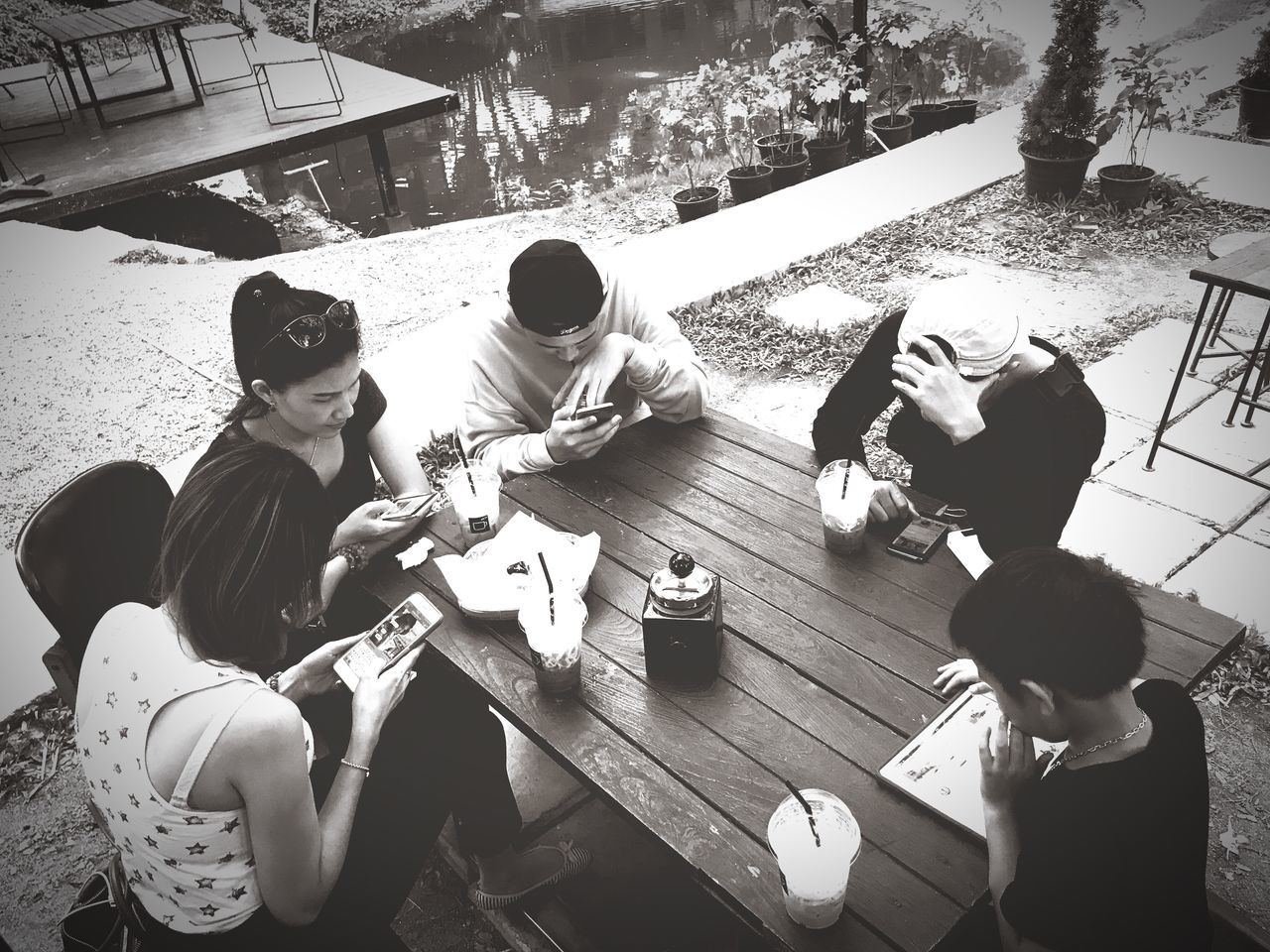 sitting, togetherness, high angle view, real people, table, boys, women, day, leisure activity, friendship, casual clothing, outdoors, girls, full length, son, men, lifestyles, bonding, young women, childhood, tree, young adult, human hand, adult, people