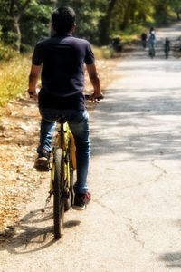 Rear view of man riding bicycle on road