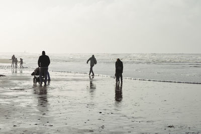 People walking on beach against sky