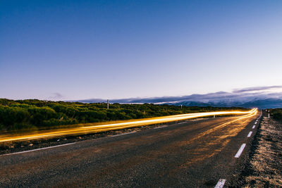 Empty road against clear blue sky